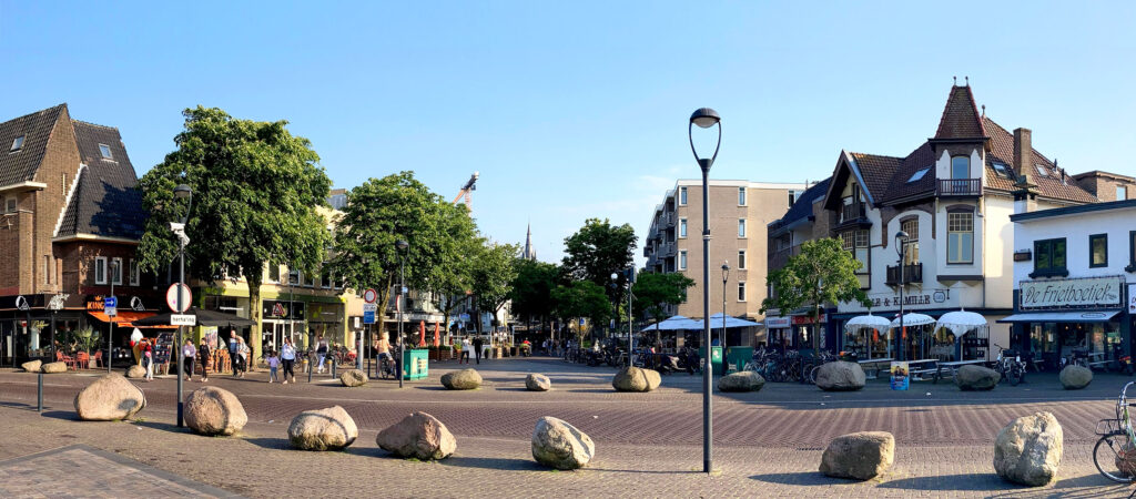 HSTotaal: bannerfoto met winkels en bomen aan brinkje tussen Langgewenst en Groest in Hilversum; begin van de Naarderstraat