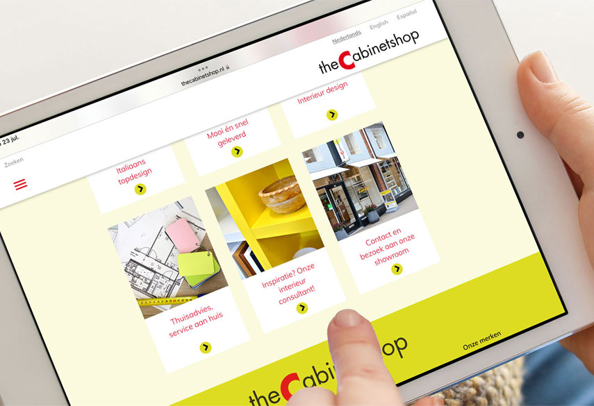 HSTotaal: twee handen met iPad; de zachtgele homepage met duidelijke knoppen van theCabinetshop, dé kastenwinkel van Den Haag