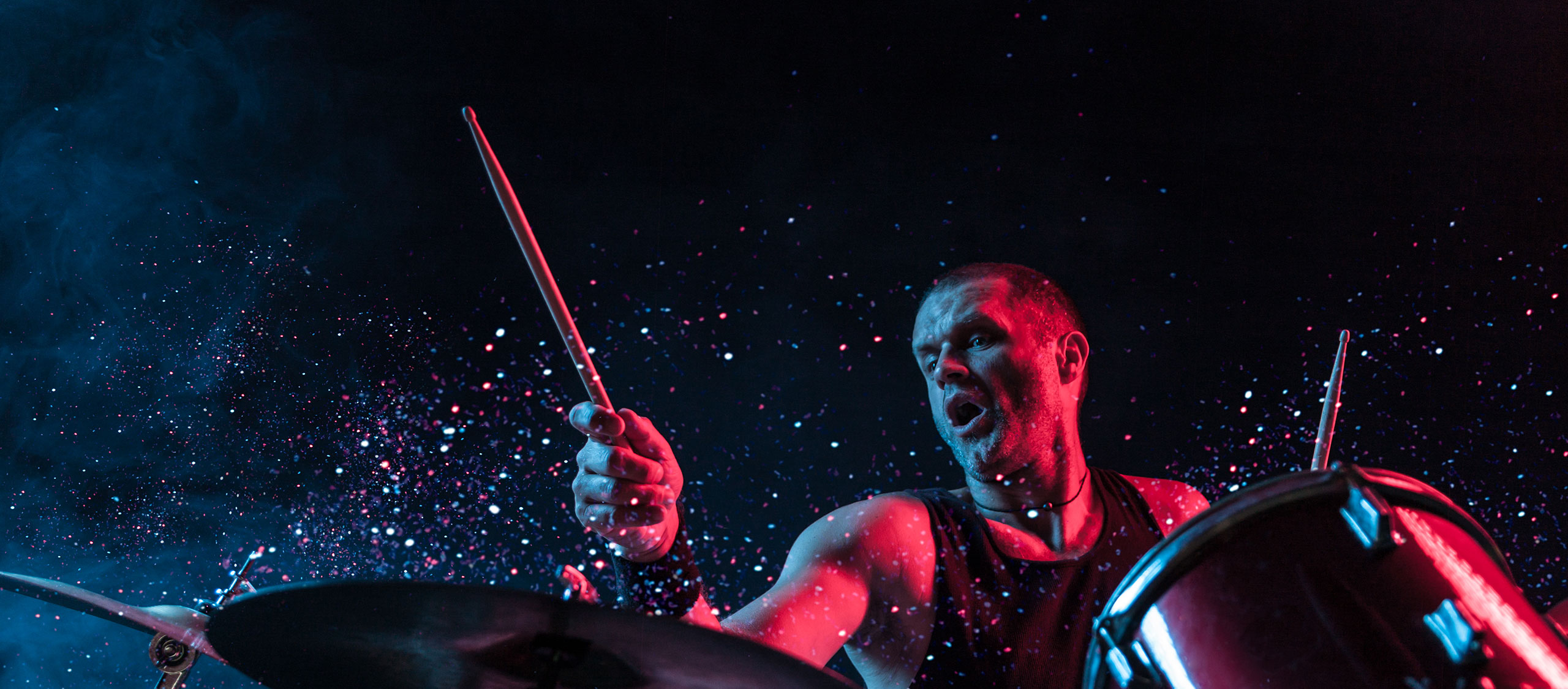HSTotaal: donkere foto van een spetterende drummer in rood en blauw licht; communicatie-concept voor PMD Accel Management