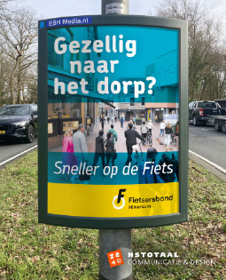 HSTotaal LinkedIn-visual: auto’s rijden op de Diependaalselaan langs de abri-poster ‘Sneller op de Fiets’ voor de Fietsersbond Hilversum
